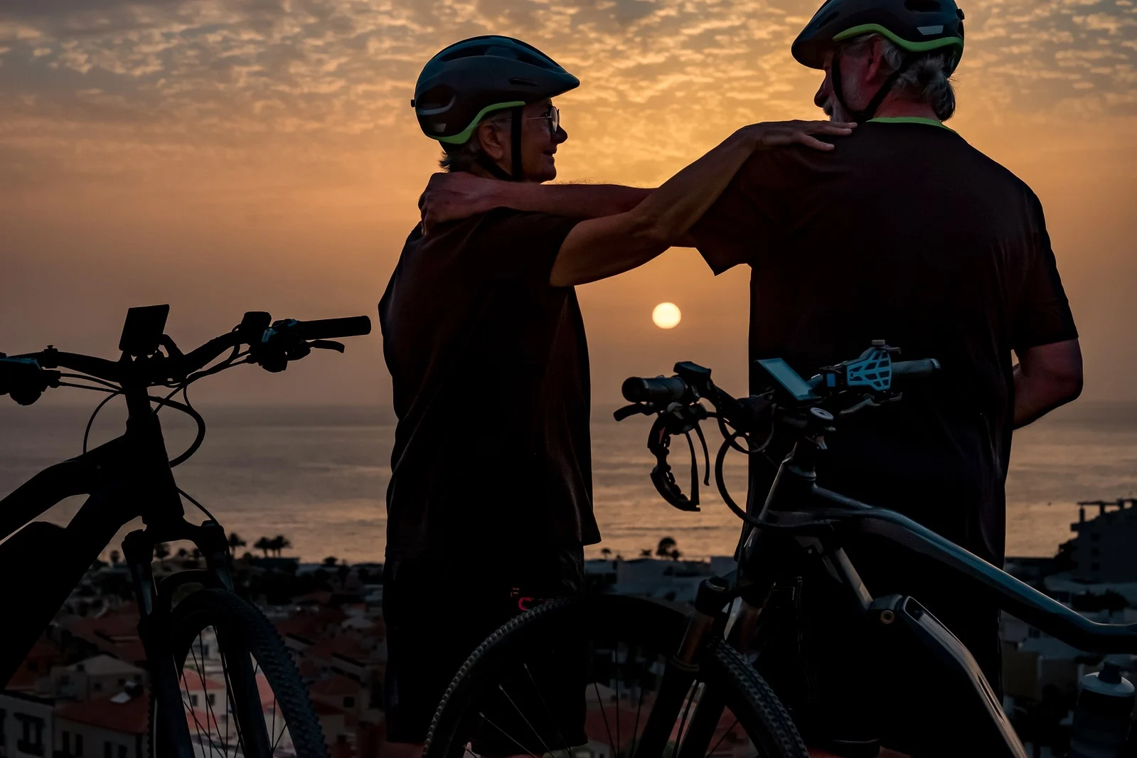 Dois ciclistas num gesto de apoio, ao pôr do sol