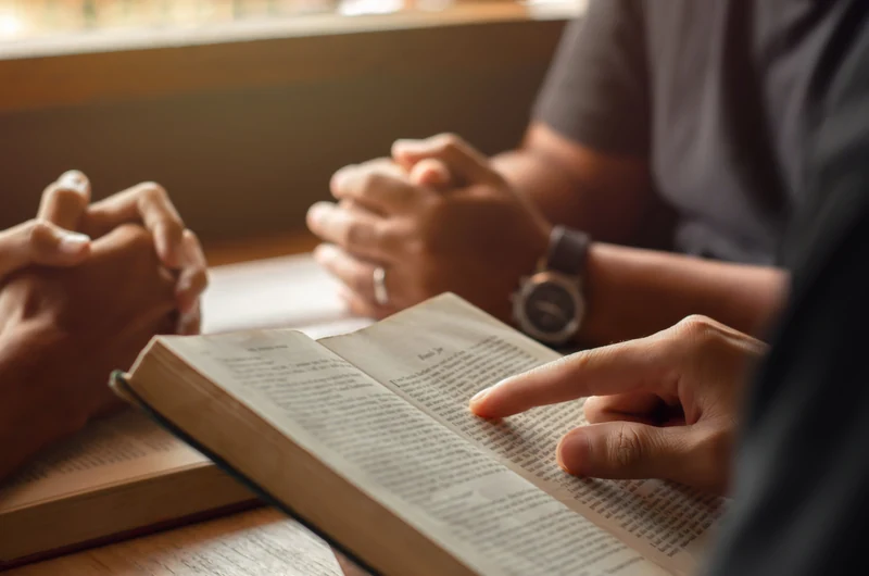 Bíblia aberta, mãos em oração e leitura partilhada