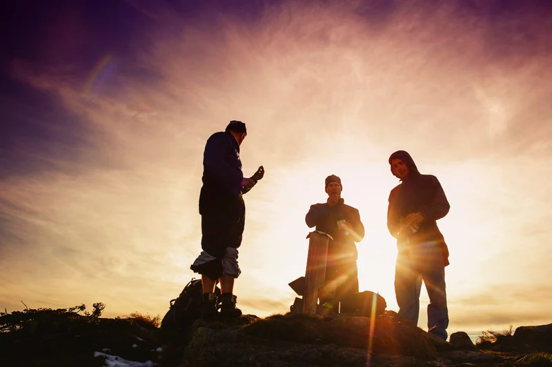 Três homens numa pausa de conversa na montanha ao amanhecer