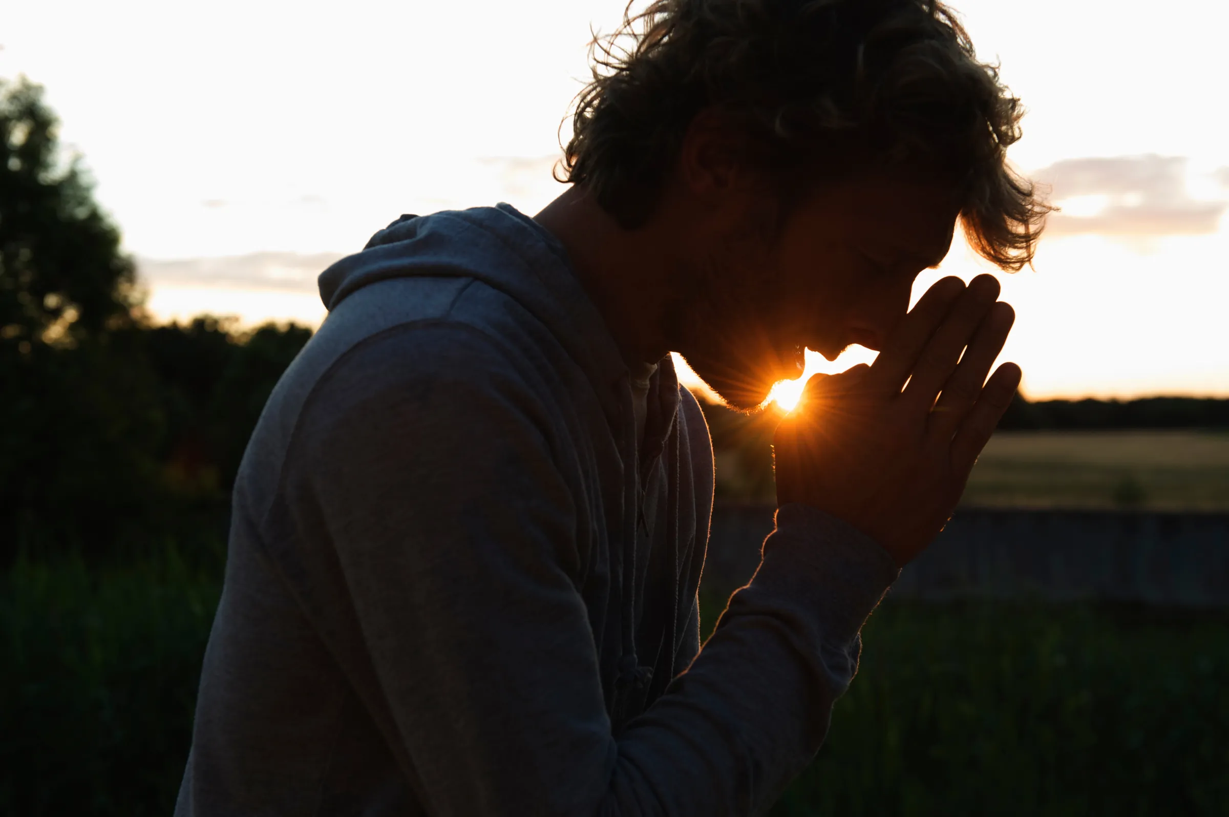 Homem em oração ao pôr do sol