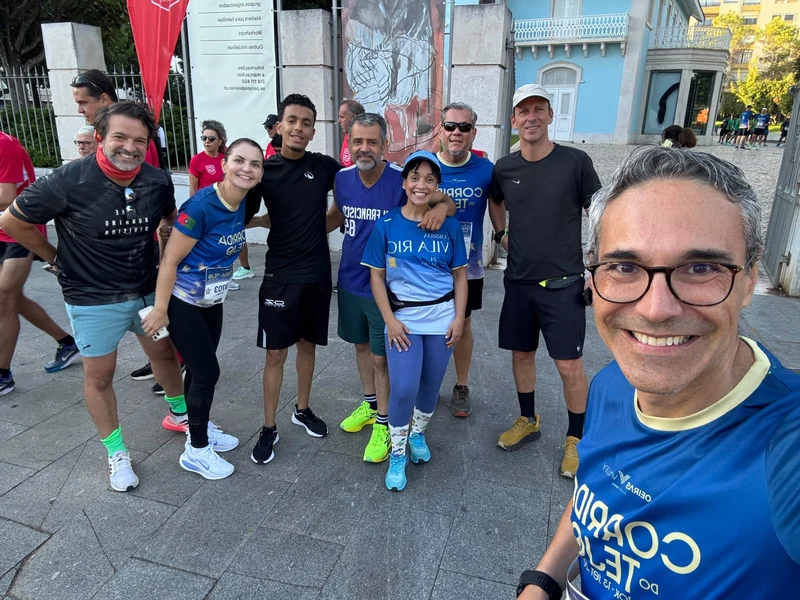 Grupo com roupa desportiva e dorsais da Corrida do Tejo reunido junto a um edifício