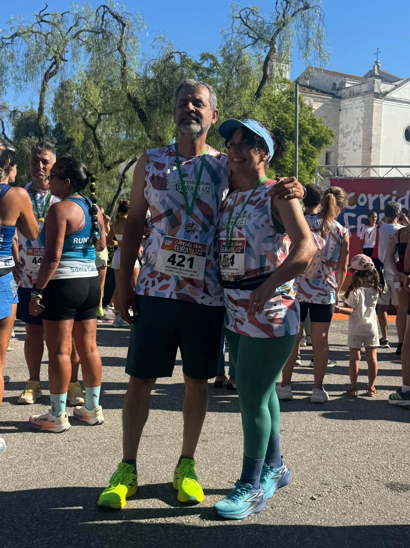 Duas pessoas com camisolas da Feira da Luz e medalhas, entre outros participantes