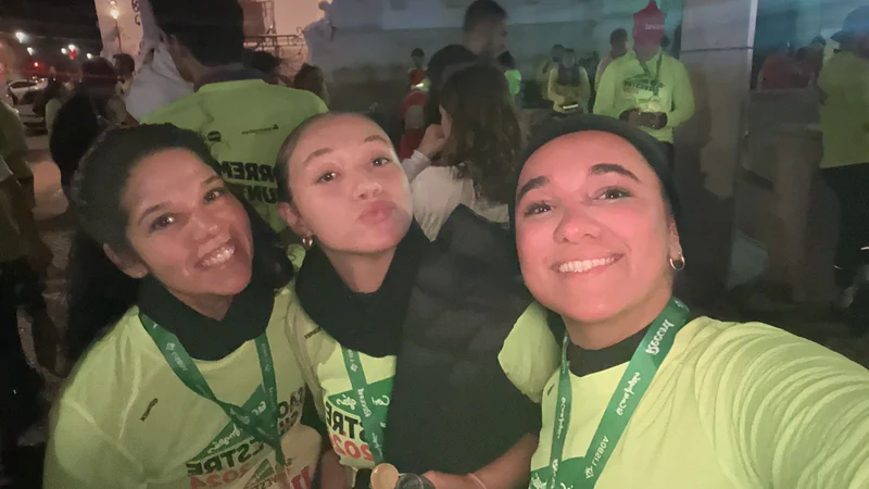 Três participantes com medalhas numa fotografia em conjunto à noite