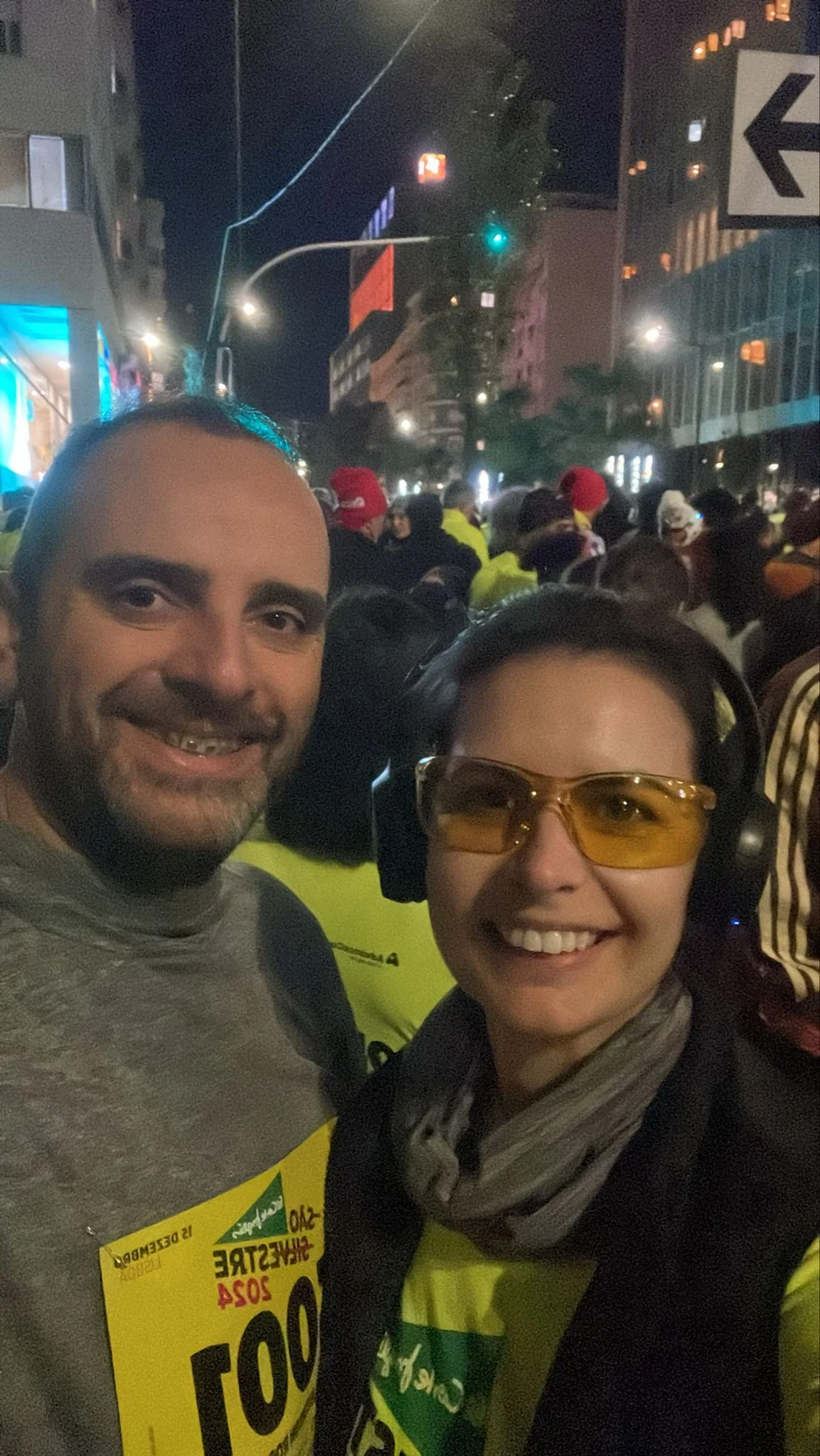 Duas pessoas com medalhas e dorsais na avenida à noite