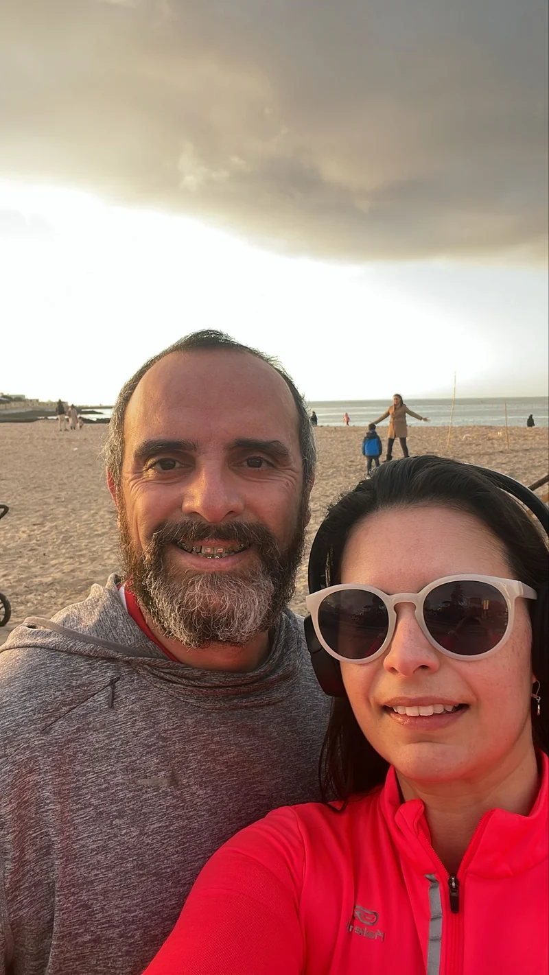 Duas pessoas com roupa desportiva junto à praia ao fim do dia