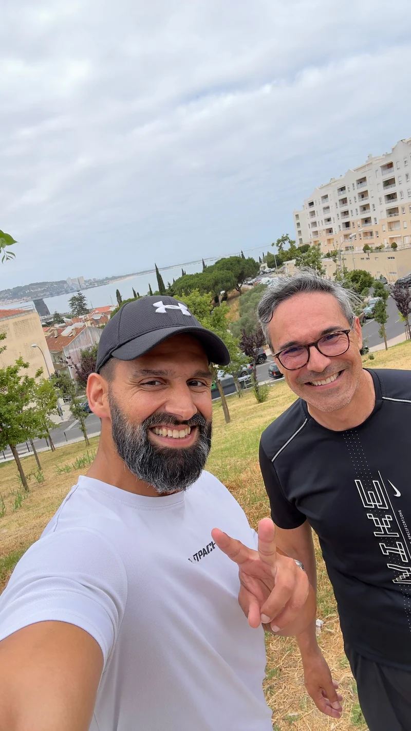 Duas pessoas com roupa desportiva numa zona verde com vista para a água